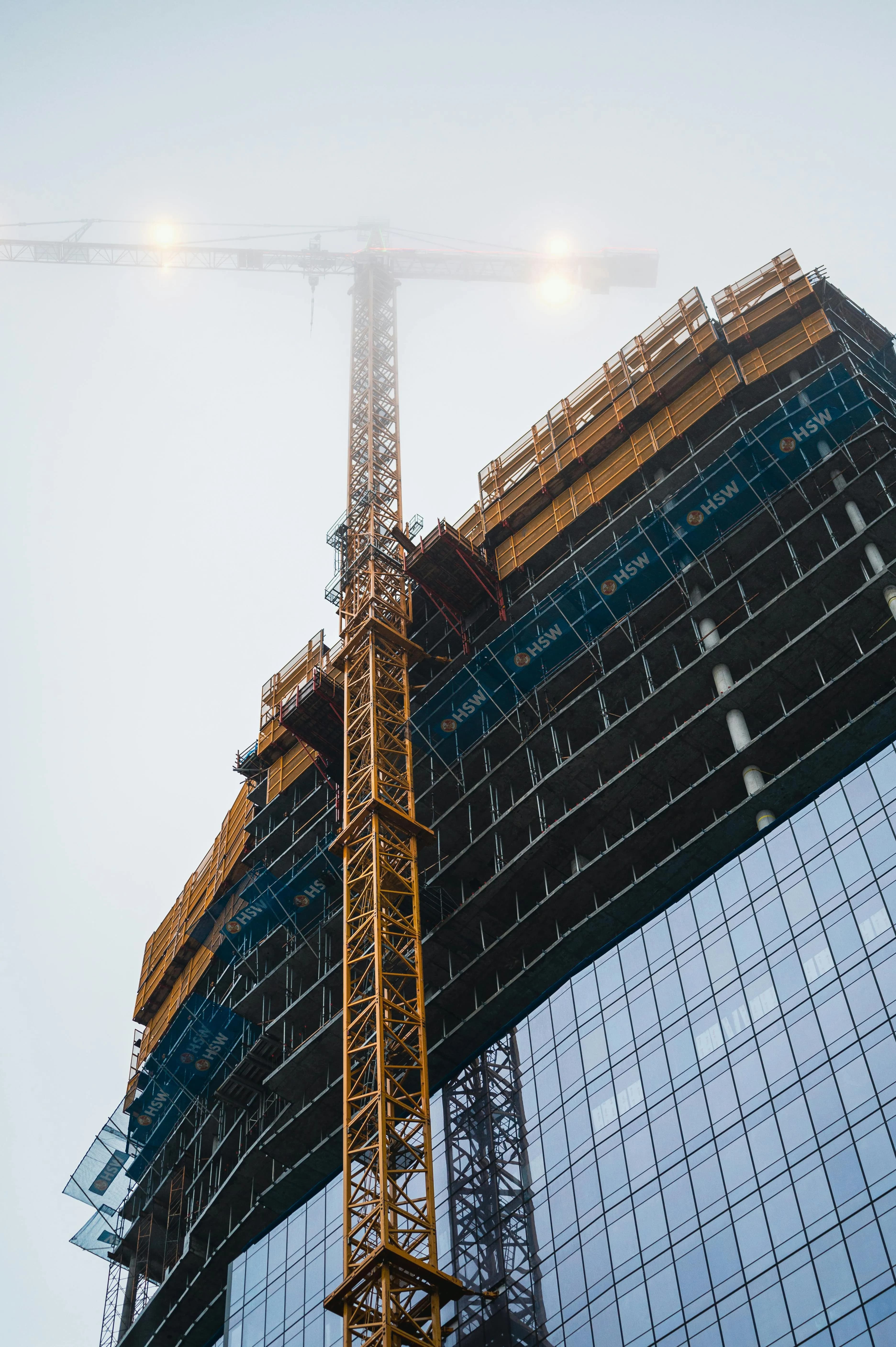 Großes Hochbau-Projekt mit beleuchtetem Baukran an verglaster Fassade – DAG Unternehmensgruppe als Generalübernehmer.
